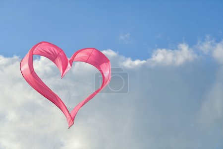 Rosafarbener Herzdrachen fliegt in den Himmel