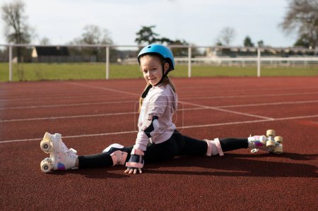 Photo for Girl sit on twine in vintage white roller skates and a helmet at the stadium - Royalty Free Image