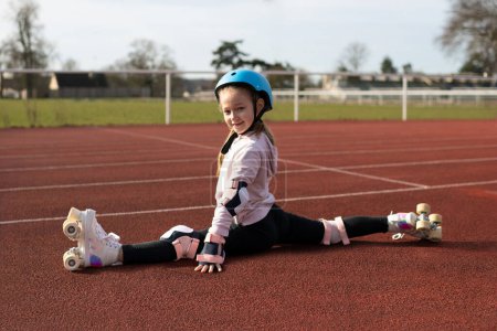 Photo for Girl sit on twine in vintage white roller skates and a helmet at the stadium - Royalty Free Image