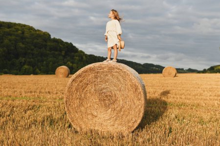 Ein Mädchen auf einem Ballen Weizen Landschaft