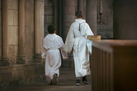 Téléchargez les photos : Enfants vêtus de tunique blanche pendant la communion à l'église - en image libre de droit
