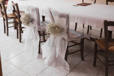 Hochzeitsstühle mit weißem Tuch und Zigeunerblumen