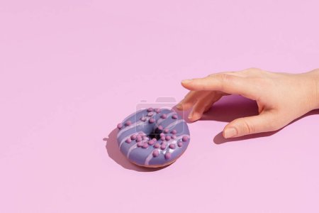 Photo for A hand with a tasty donut on a color background - Royalty Free Image
