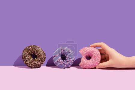 Photo for A hand with a tasty donuts on a color background - Royalty Free Image