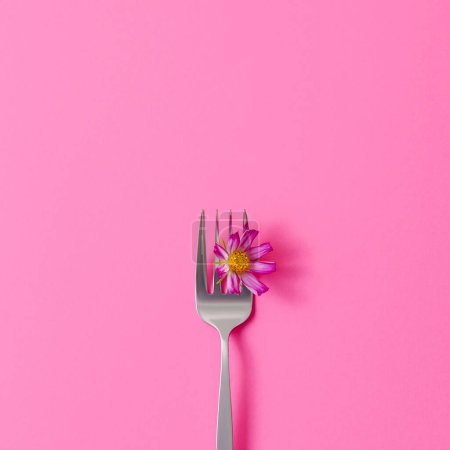 Foto de Flor rosa sobre tenedor sobre fondo rosa. Fondo de color creativo, espacio de copia, concepto mínimo - Imagen libre de derechos