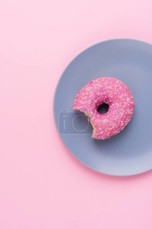 Photo for Top view of one pink donut on a blue plate on pink background, copy space - Royalty Free Image
