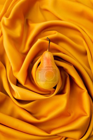 Foto de Fresca pera jugosa sobre un satén de seda amarillo. Plano, vista superior, monocromo - Imagen libre de derechos