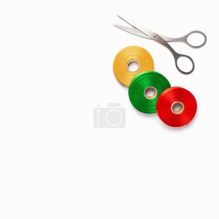 Photo for Set of colorful satin ribbon spools and scissors on white background. Top view, copy space - Royalty Free Image
