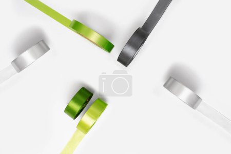 Téléchargez les photos : Ensemble de bobines de ruban de satin vert et gris sur fond blanc. Ruban textile bobines, vue de dessus - en image libre de droit