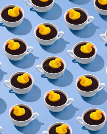 Téléchargez les photos : Motif créatif tendance en tasse à café avec un canard en caoutchouc jaune sur un fond bleu - en image libre de droit