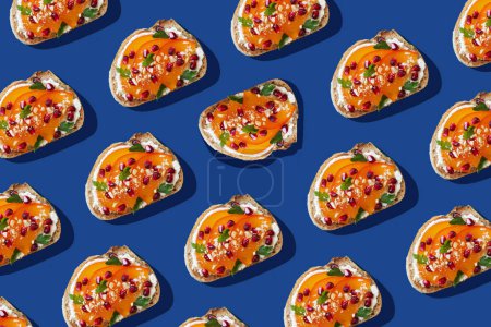Photo for Pattern of toasts with cream cheese, persimmon and pomegranate seeds on blue background. Creative food photo concept, top view - Royalty Free Image