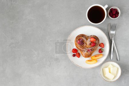 Photo for Valentine's day breakfast on gray background. Bun with butter and berries on a white plate and a cup of coffee. Top view, copy space - Royalty Free Image