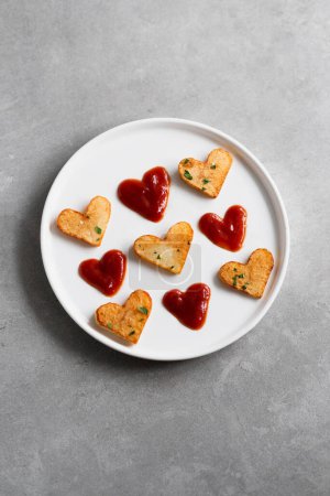 Photo for Valentine's Day roasted potato hearts and red sauce hearts on a white plate on concrete background. Romantic food ideas for Valentine's Day. Top view, copy space - Royalty Free Image