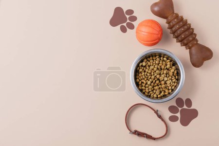 Photo for Dry dog food bowl and toys on neutral background. National Puppy Day concept, top view, copy space - Royalty Free Image