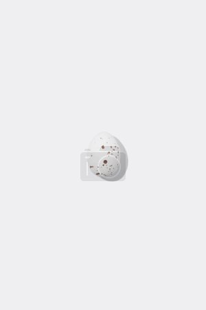 Foto de Un huevo de Pascua moteado blanco que proyecta sombra sobre fondo blanco, concepto de minimalismo, espacio de copia - Imagen libre de derechos