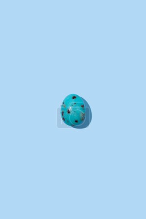 Photo for One blue speckled Easter egg casting shadow on blue background, minimalism concept, copy space - Royalty Free Image