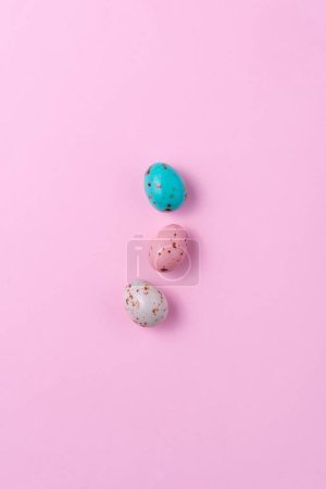 Téléchargez les photos : Oeufs de Pâques de couleur chocolat mouchetés sur un fond rose. Minimalisme Pâques concept, espace de copie, vue de dessus - en image libre de droit