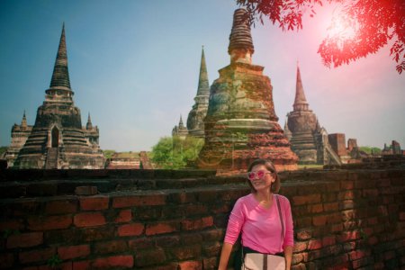 Téléchargez les photos : Beautiful woman standing against old brick wall with asian temple background - en image libre de droit