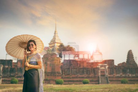 Téléchargez les photos : Femme asiatique portant thai costume traditionnel stand avec parapluie contre le vieux temple dans ayutthaya patrimoine de l'humanité de thailand de l'Unesco - en image libre de droit