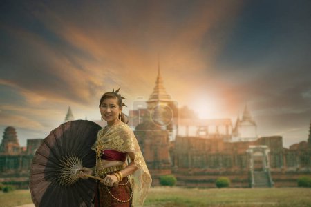 Téléchargez les photos : Belle femme asiatique portant thai costume de tradition debout contre le vieux temple à Ayutthaya site du patrimoine mondial de l'Unesco central de Thaïlande - en image libre de droit