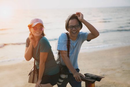 Téléchargez les photos : Couples asiatiques se détendre avec bonheur visage sur la plage coucher de soleil - en image libre de droit