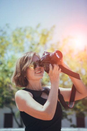 Téléchargez les photos : Asiatique femme prendre une photo avec dslr caméra debout en plein air contre belle lumière du soleil - en image libre de droit