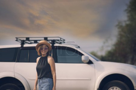Téléchargez les photos : Belle femme debout en face de la voiture SUV avec toothy sourire visage de bonheur - en image libre de droit