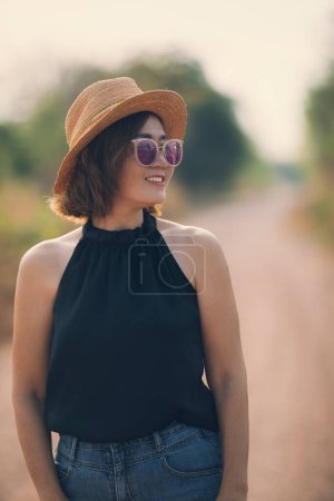 Téléchargez les photos : Belle asiatique femme porter paille chapeau debout en plein air avec toothy sourire visage - en image libre de droit