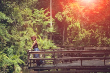 Téléchargez les photos : Femme debout sur le patio en bois contre la forêt vert profond - en image libre de droit