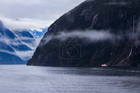 Téléchargez les photos : Bateau de croisière à côté de la montagne à milfordsound fiordland parc national sud de la Nouvelle-Zélande - en image libre de droit