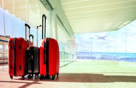 Foto de Pila de equipaje de viaje en el edificio de la terminal del aeropuerto con el avión de pasajeros volando fondo - Imagen libre de derechos