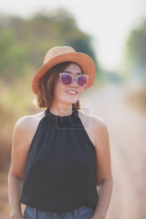Téléchargez les photos : Belle asiatique femme porter paille chapeau toothy sourire avec bonheur debout en plein air contre belle lumière du matin - en image libre de droit