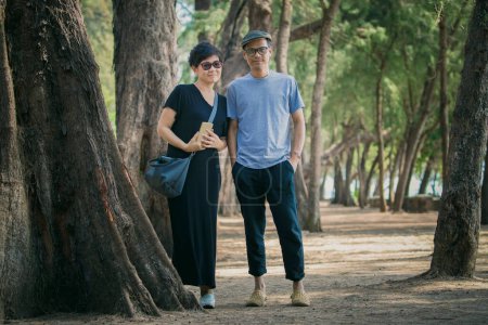Téléchargez les photos : Relaxant asiatique homme et femme portant style de vie décontracté debout avec détente sur pin parc plage - en image libre de droit
