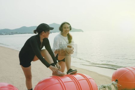 Téléchargez les photos : Deux asiatique femme étirement avant exercice sur mer plage - en image libre de droit