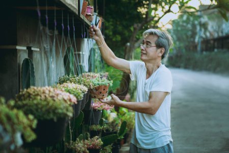 Téléchargez les photos : Asiatique tenant pendaison plante d'intérieur pot dents souriant avec bonheur visage debout extérieur - en image libre de droit