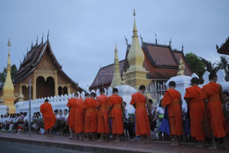 Téléchargez les photos : Luang prabang laos - 22 juillet2023 : villageois et touristes offrant du riz collant au moine bouddhiste tôt le matin au wat sensoukharam le plus célèbre monument de luang prabang - en image libre de droit