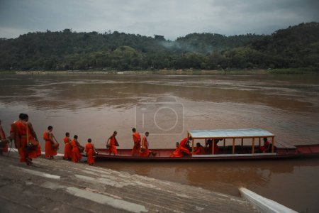Téléchargez les photos : Luang prabang-july19,2023 : moine bouddhiste approche fot en bateau domestique au temple wat xiang thong à côté de la rivière maekong à luang prabang au nord de laos l'une des destinations les plus populaires pour voyager à trrvaling - en image libre de droit