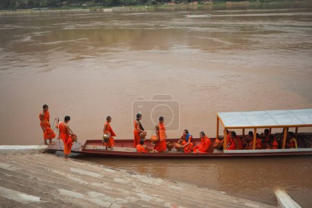 Téléchargez les photos : Luangprabang-july19,2023 : moine et bateau domestique au temple wat xiang à côté de la rivière maekong à luang prabang au nord de laos l'une des destinations les plus populaires - en image libre de droit