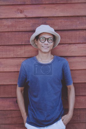 Téléchargez les photos : Asiatique adulte homme toothy sourire avec bonheur visage debout contre mur en bois - en image libre de droit