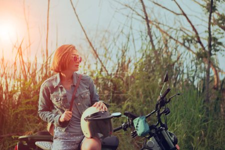 Téléchargez les photos : Femme célibataire tenant un casque de sécurité assis sur la moto - en image libre de droit