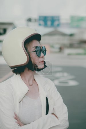 Téléchargez les photos : Asiatique femme portant anti-knock casque debout sur ville route côté - en image libre de droit