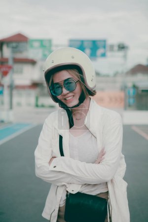 Téléchargez les photos : Asiatique femme portant blanc sécurité casque debout sur ville route toothy sourire avec bonheur - en image libre de droit
