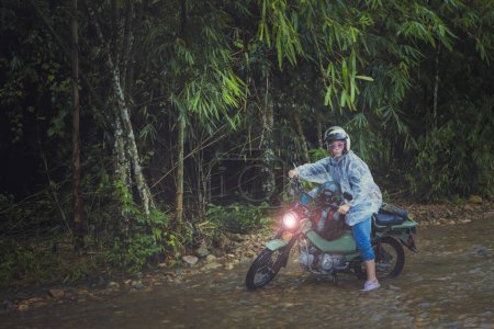 Téléchargez les photos : Jolie femme chevauchant petite enduro moto traversant ruisseau peu profond - en image libre de droit