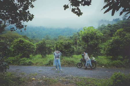 Téléchargez les photos : Couples de motards tirant petite moto enduro sur piste de campagne parmi les chutes de pluie - en image libre de droit