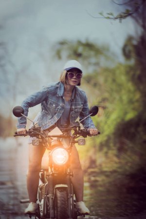 Téléchargez les photos : Belle femme chevauchant petite moto enduro sur piste de terrain - en image libre de droit