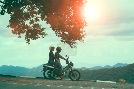 Téléchargez les photos : Couples portant un casque de sécurité assis sur une petite moto enduro contre la belle scène de montagne naturelle au parc national de Khaoyai Thaïlande - en image libre de droit