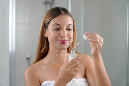 Femme beauté tenant la pipette prête à appliquer de l'acide hyaluronique à la maison. routine de soins de la peau.