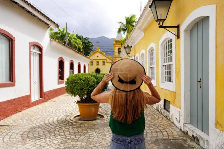 Photo for Tourism in Sao Sebastiao, Brazil. Back view of beautiful fashion girl visiting colonial town of Sao Sebastiao, on Sao Paulo coast, Brazil. - Royalty Free Image