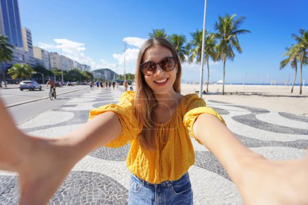 Téléchargez les photos : Tourisme à Rio de Janeiro. Belle fille souriante prend autoportrait sur la promenade de plage Copacabana, Rio de Janeiro, Brésil. - en image libre de droit