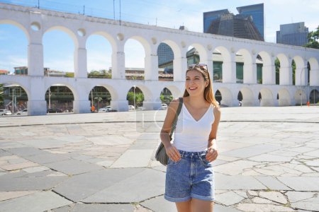 Foto de Retrato de una joven turista visitando el barrio de Lapa con Acueducto Carioca (Arcos da Lapa) en Río de Janeiro, Brasil - Imagen libre de derechos